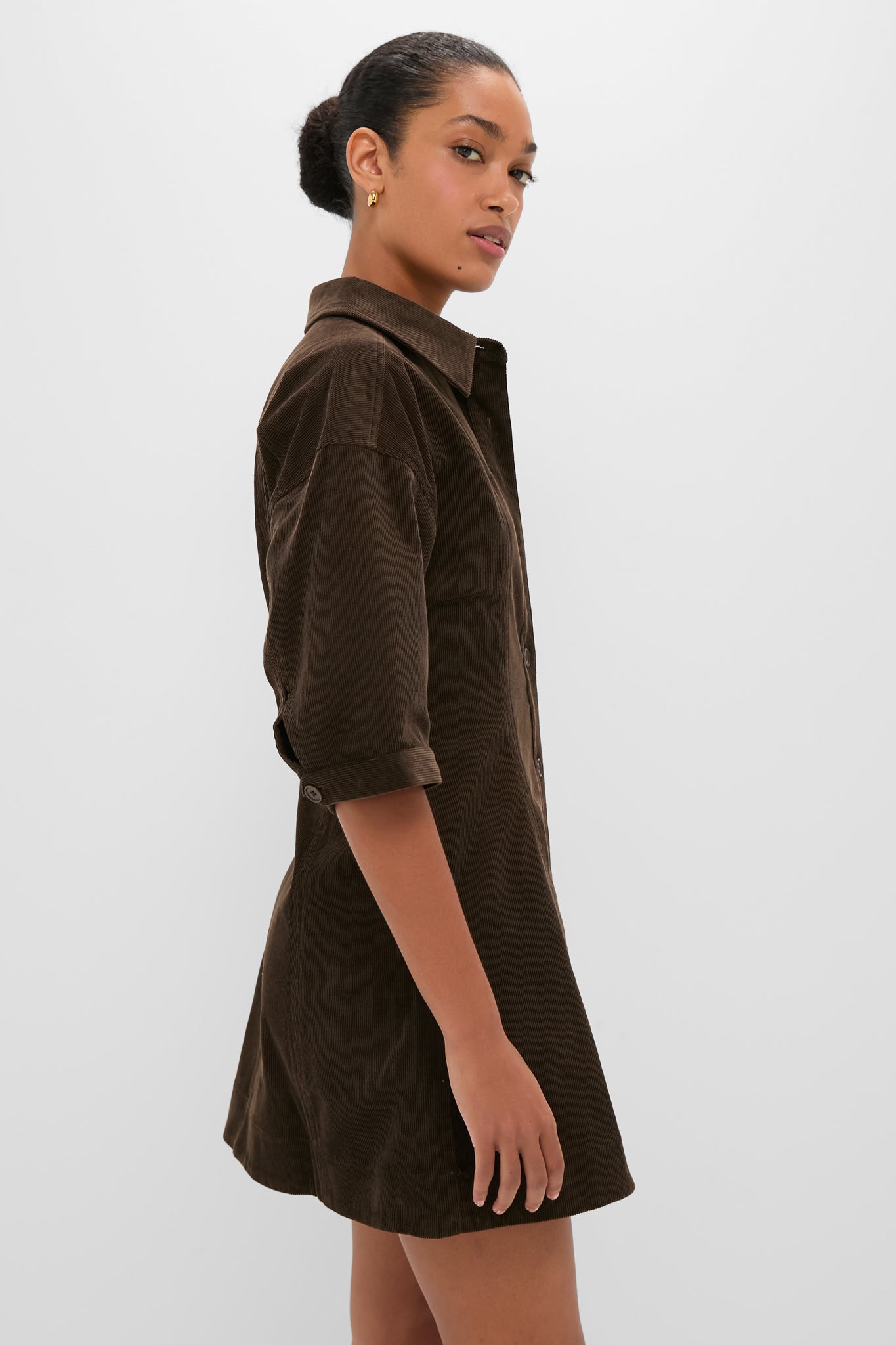 Young woman in profile wearing the classic Carob Luz Mini Dress with lantern sleeves and fitted waist, embodying an effortless, high-end style.