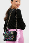 Woman wearing a classic, effortless black top and metallic skirt, showcasing the Multi Sequin Crossbody with a fun, high-end gold chain and vibrant sequin details.
