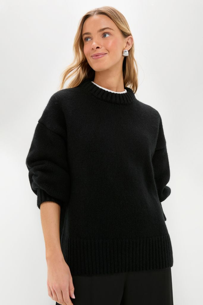 Light-skinned woman models the classic Black Genevieve Cashmere Wool Blend Crewneck Sweater, showcasing its ribbed finishes and boxy fit for an effortless, high-end, fun look.