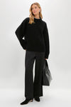 Model in Black Genevieve Cashmere Wool Blend Crewneck Sweater, embodying classic, effortless style with chunky knit and ribbed details, paired with chic wide-leg trousers and accessories.