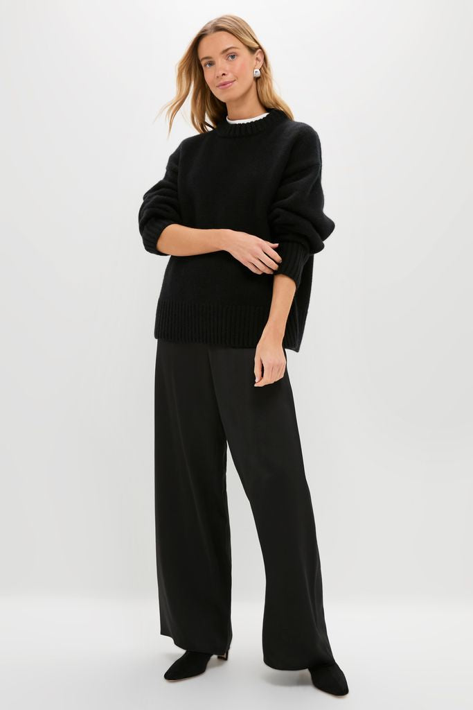 Young woman models the Black Genevieve Cashmere Wool Blend Crewneck Sweater, a classic, effortlessly chic, and high-end piece with ribbed finishes and a chunky soft knit.