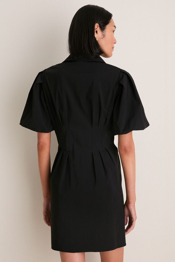 Person wearing the Black Mini Delaney Dress, featuring a classic spread collar and effortless puff sleeves, embodies a high-end, fun style that transitions seamlessly from work to play.