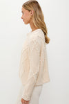 Woman wearing Cream Cable Knit Pearl Collins Cardigan with pearl embellishments, showcasing an effortless, high-end look, embodying classic style and fun elegance.