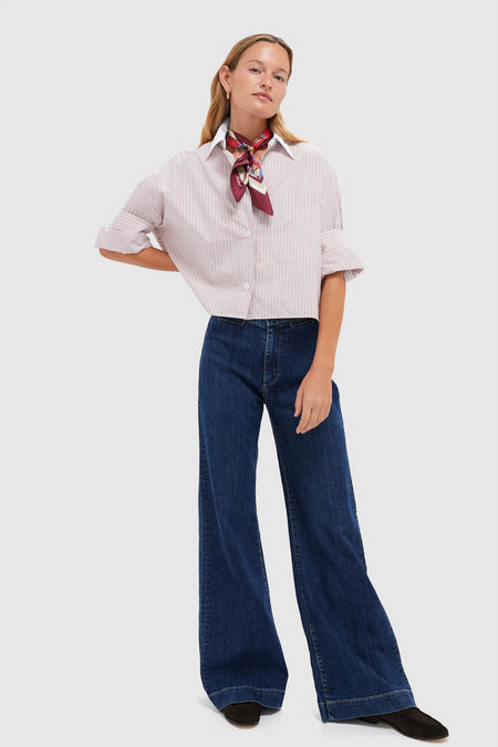 Model wearing the Spanish Villa and White Next Ex Shirt, a classic, cropped button-down with pink-and-white stripes and rolled sleeves, paired with high-waisted, wide-leg jeans.