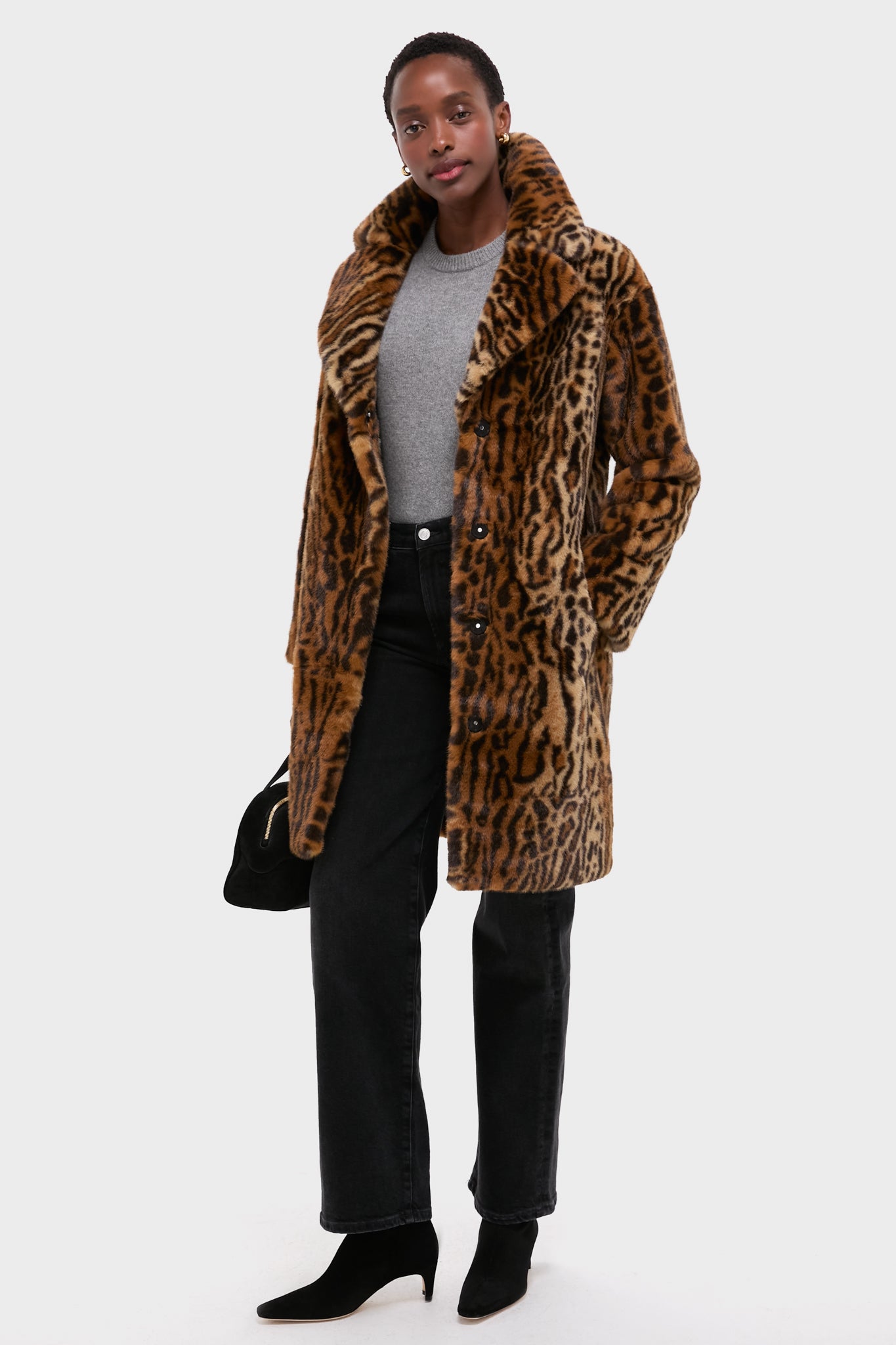 Model showcases an effortless, high-end style with a classic black suede mini bowling bag, featuring chic gold-tone hardware and sprout handles, exuding fun sophistication.