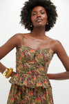 A woman models a Hyacinth House sleeveless floral peplum-waisted cocktail dress with thin straps and a sweetheart neckline, accessorized with gold jewelry against a plain background.