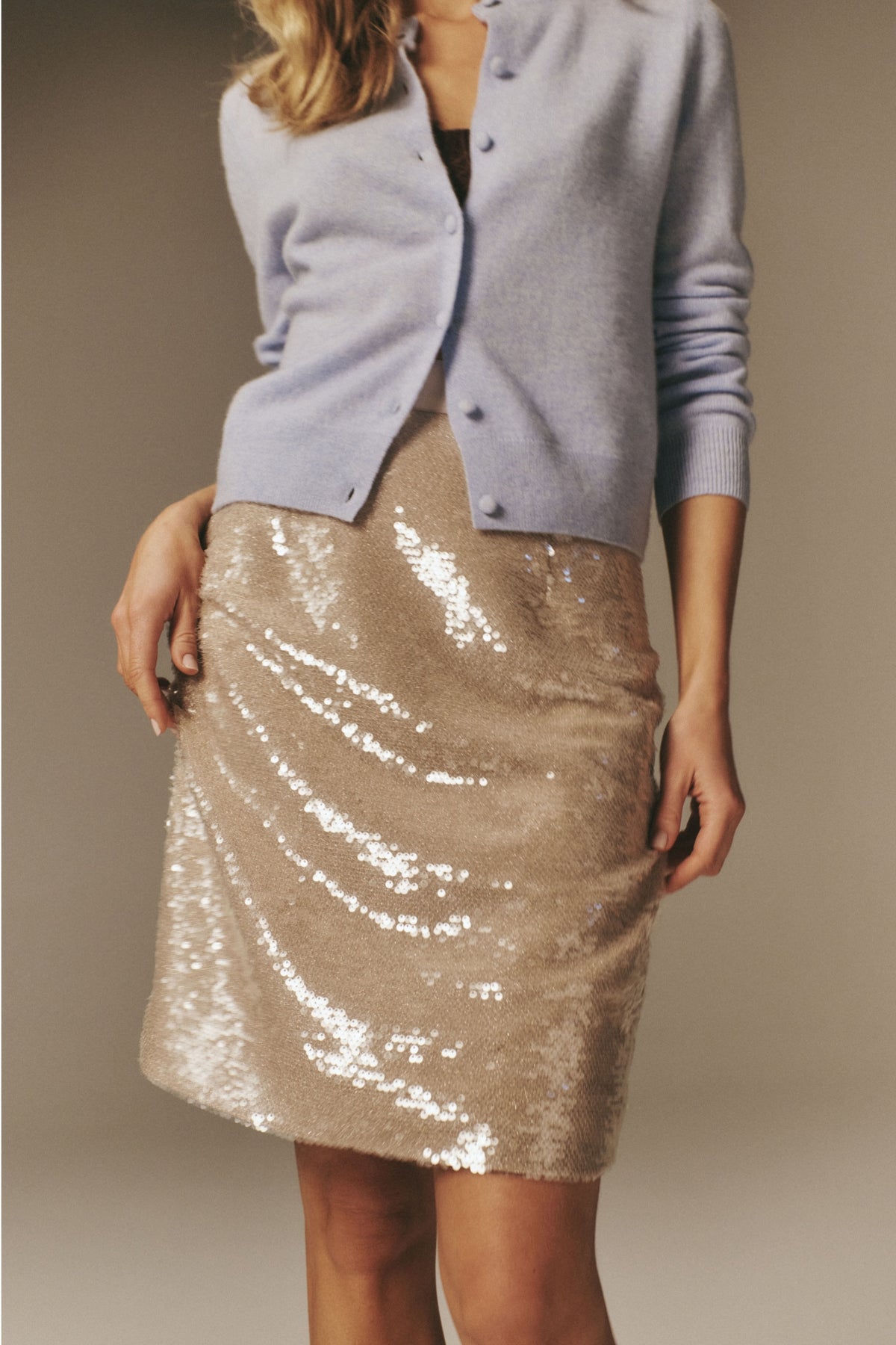 The Champagne Sequin Clayton Midi Skirt features a classic pencil silhouette with an effortless, high-end sparkle, perfect for fun holiday gatherings.