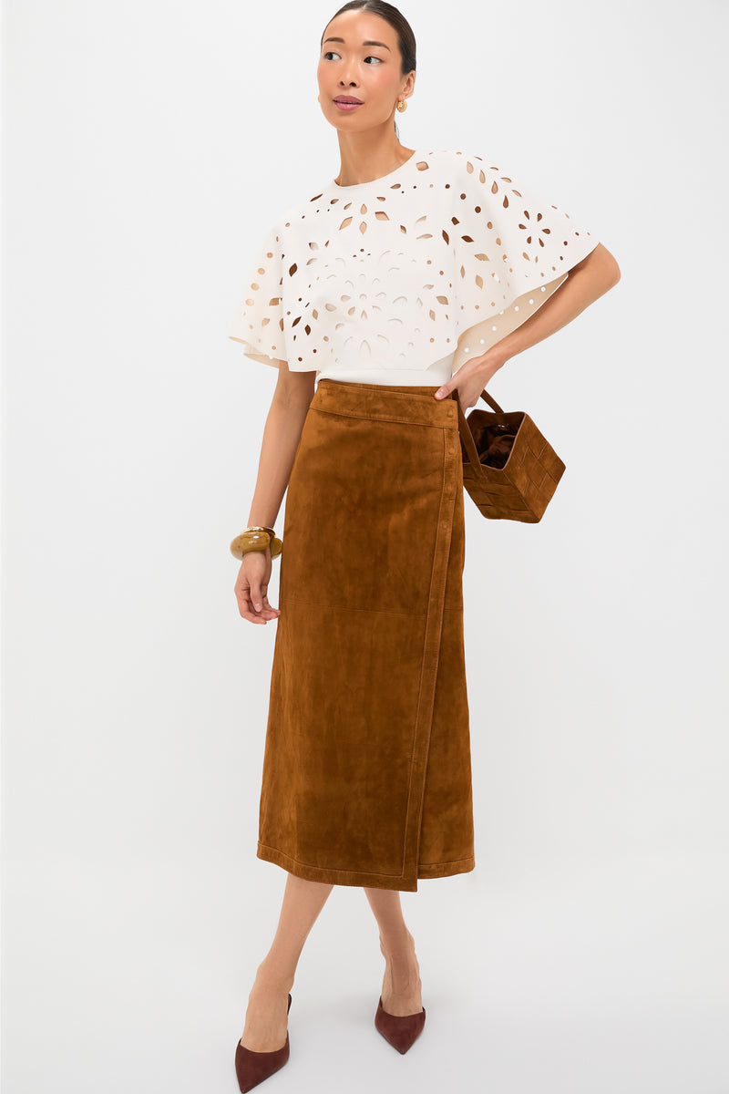 Model wears the classic Nutmeg Winona Skirt, an effortless high-end suede midi with a wrap design, styled with a cape top, pumps, and a basket bag.