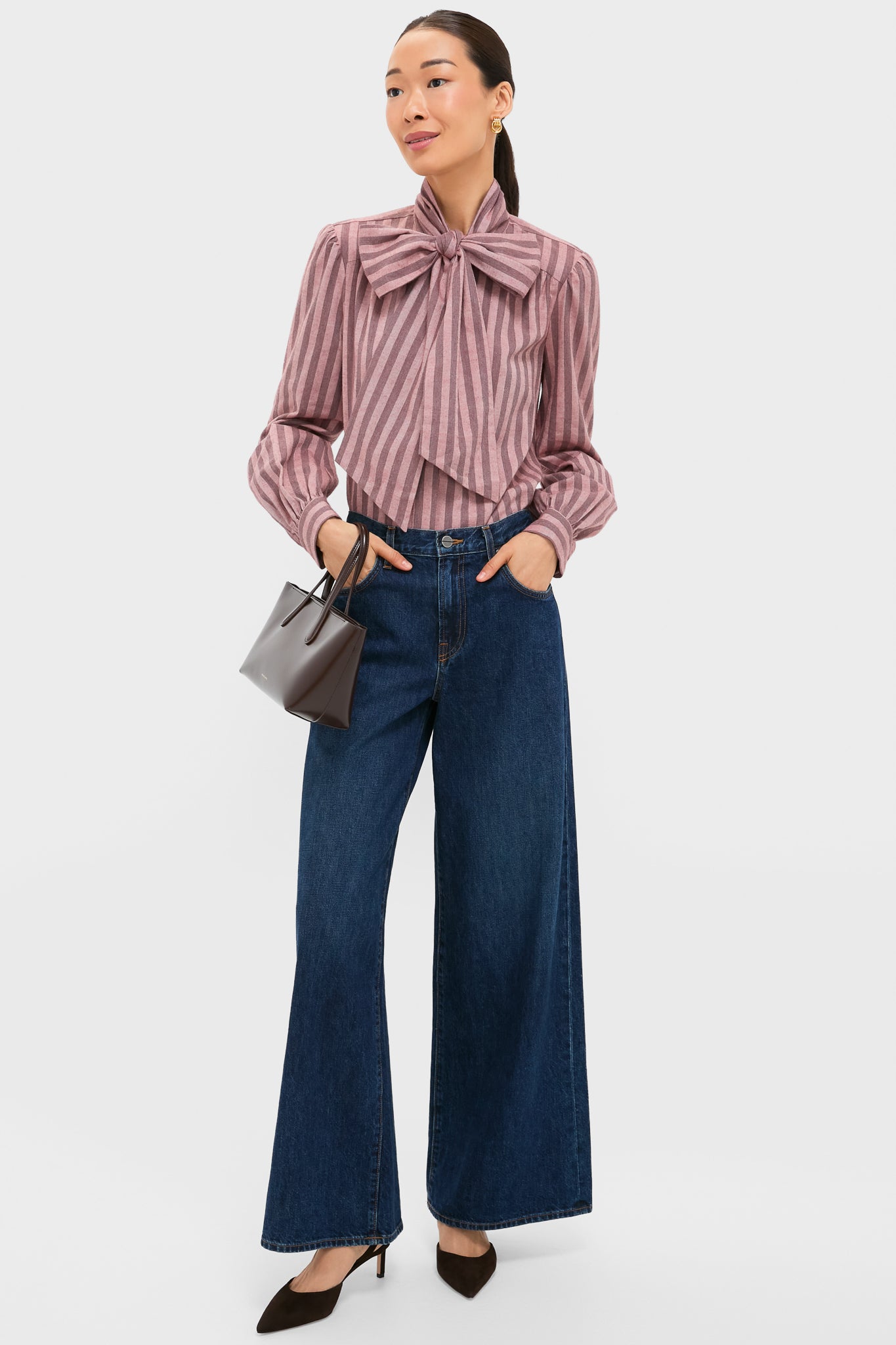 Woman models the classic Mauve Stripe Brianna Bow Blouse, styled effortlessly with high-end jeans and accessories, embodying fun sophistication.