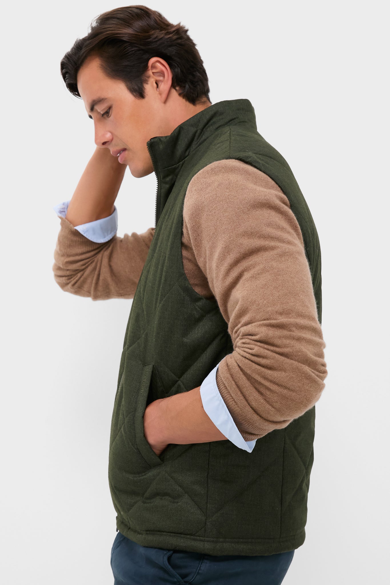 Young man in an Olive Winter Finn Gilet, a classic, quilted vest with a high collar and practical pockets, exuding effortless, high-end style for unpredictable weather.