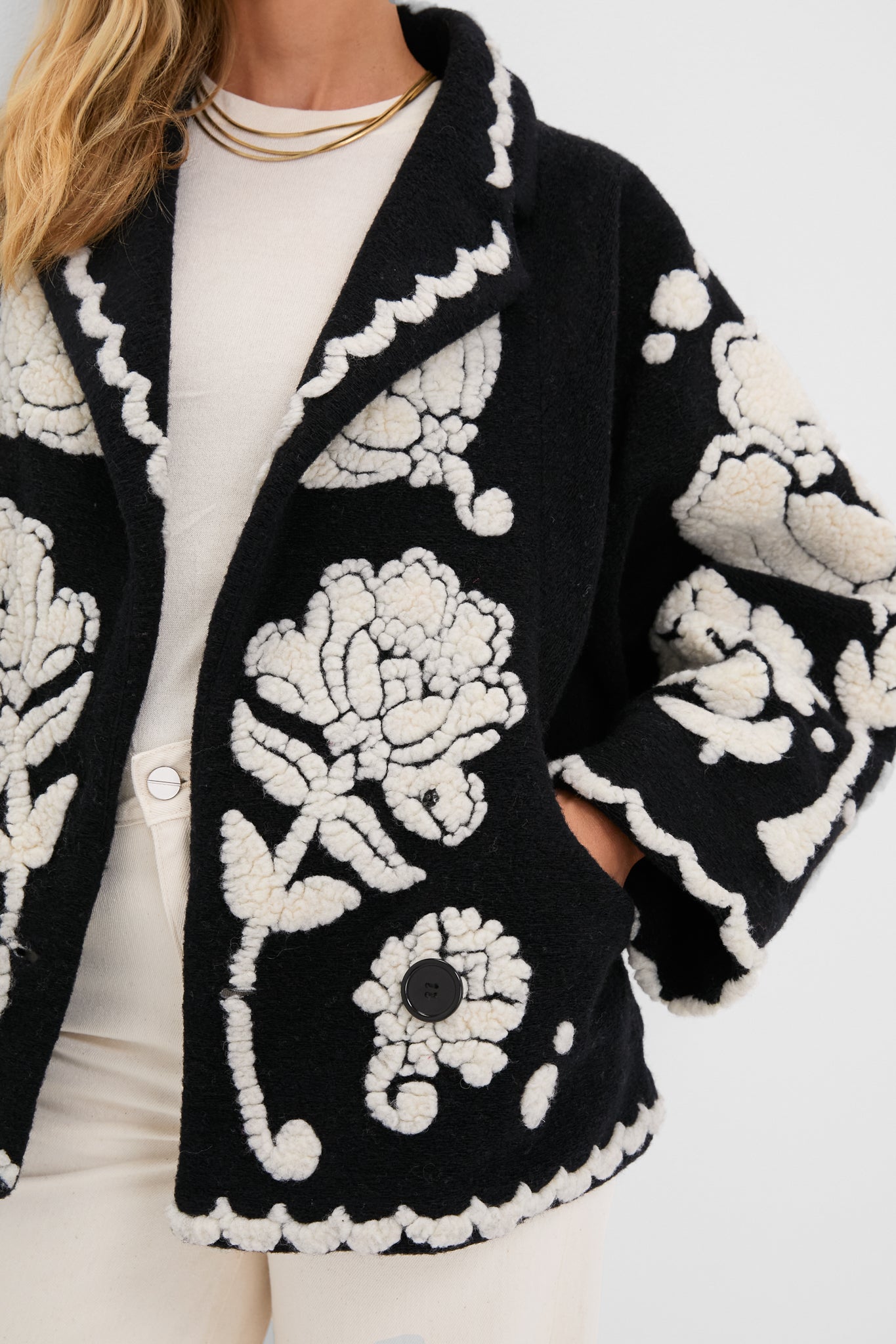 Classic Black Cream Floral Arabesque Fleece Coat with raised floral appliqués, notched collar, and scalloped trim, effortlessly layered over a cream top and pants.