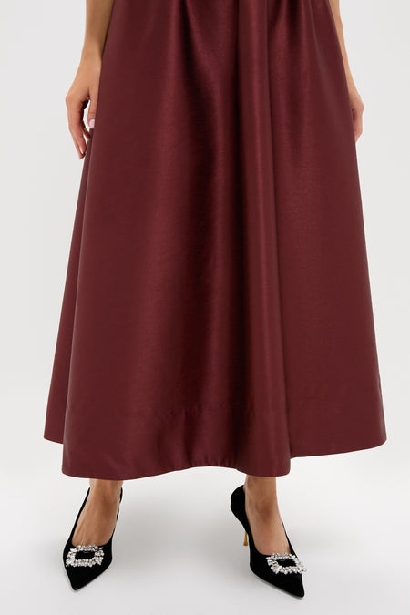 Oxblood Dupioni Bow Esme Dress in rich burgundy satin, paired with black pumps featuring rhinestone buckles, embodies classic, effortless elegance for fun, high-end events.