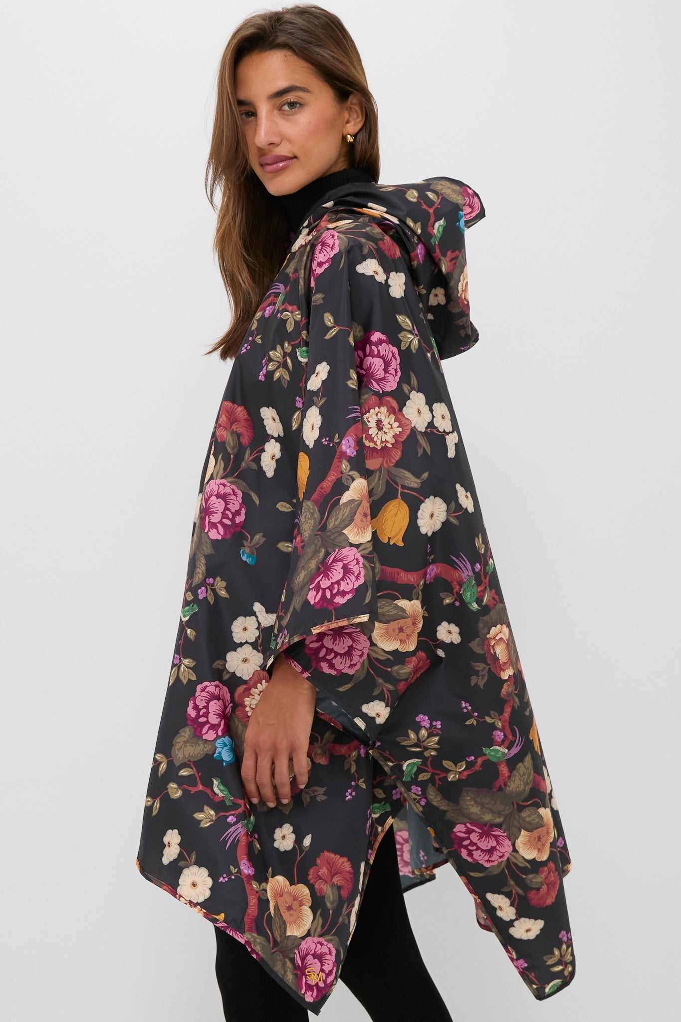 Woman wearing a classic, high-end Black Floral Barbour x Tuckernuck Poncho, effortlessly blending fun and fashion with its colorful floral design and practical, packable features.