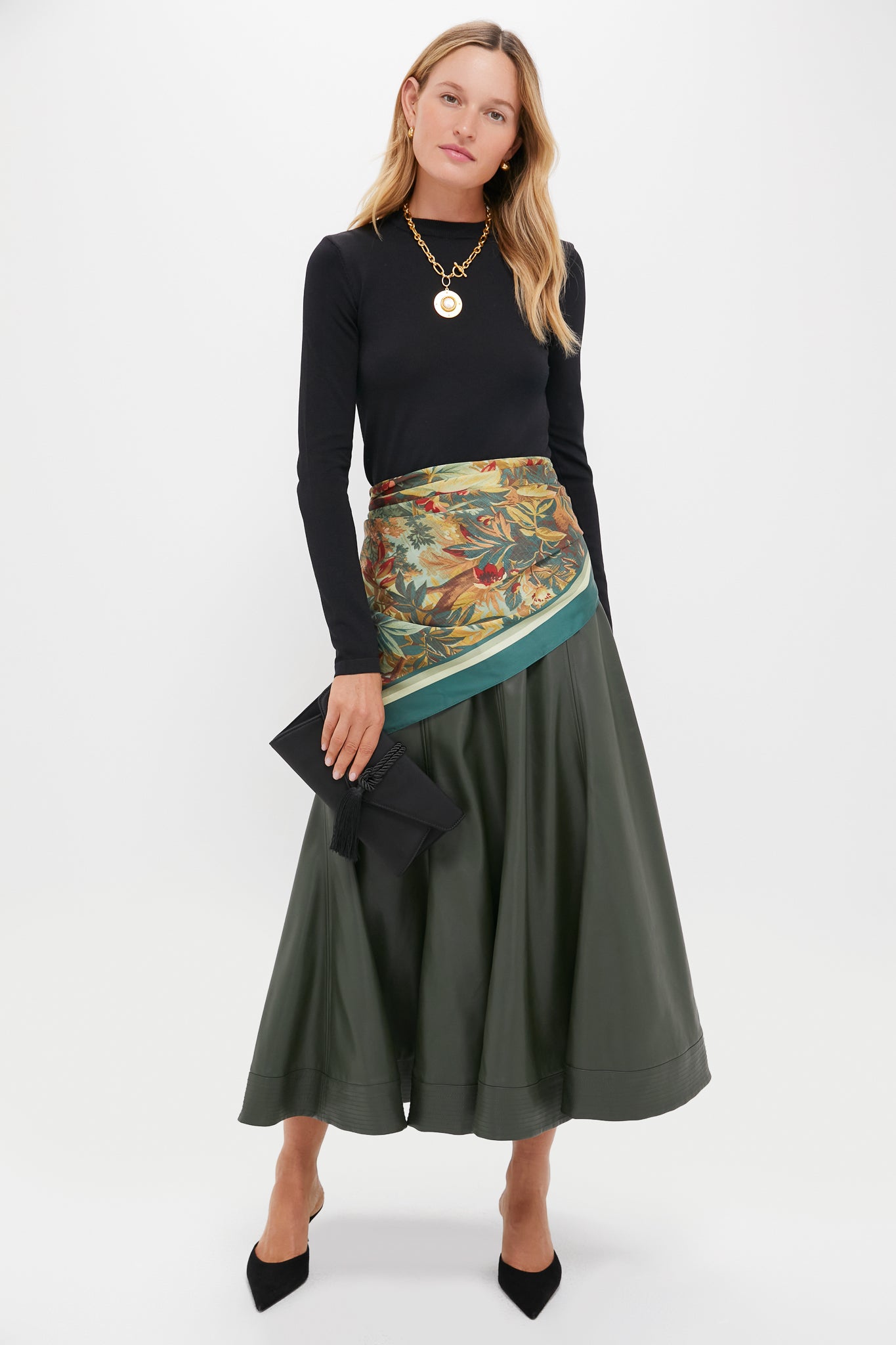 Woman styled in an effortless, high-end look with a classic Black Satin Gabrielle Clutch featuring a braided tassel, perfect for fun, sophisticated evenings out.