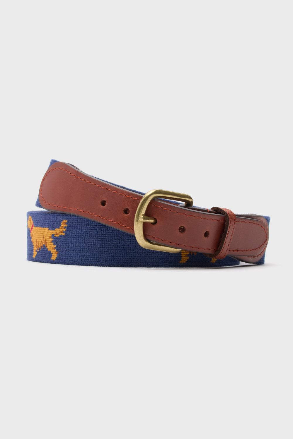A blue adjustable Smathers and Branson belt featuring hand-stitched needlepoint golden retrievers, brown leather ends, and a brass buckle.