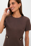 Young woman in a classic, effortless Chocolate Brown Zarah Midi Dress, featuring gold button tabs at the waist and sculptural gold earrings, exuding fun and high-end style.