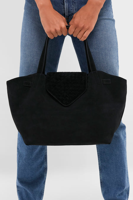 Black Suede Blaine Tote: A classic, high-end bag with an effortless, fun design featuring a woven flap, perfect for carrying essentials with style.