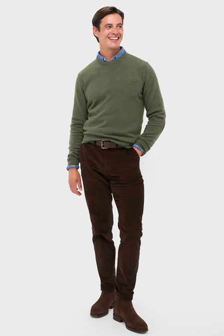 Man modeling the classic Olive Essential Patch Crew Neck Sweater with leather elbow patches, layered over a shirt, paired with corduroy trousers and Chelsea boots for an effortless, high-end look.