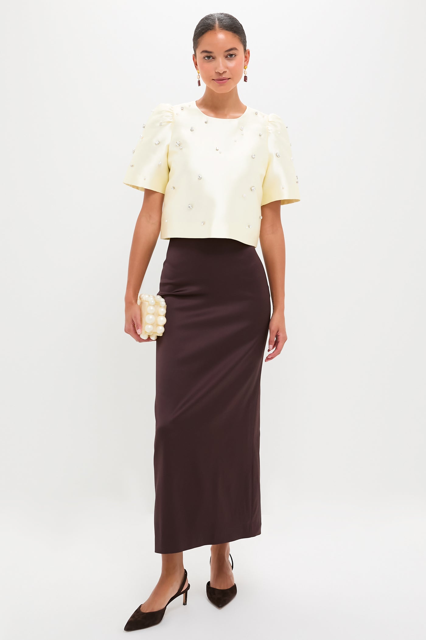The Ivory Olivia Top exudes effortless glamour with its classic pearl and rhinestone embellishments, perfectly paired with a sleek chocolate skirt for a high-end, fun look.