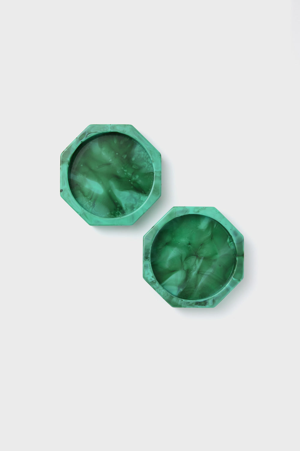 Two green, octagonal wine coasters from Tuckernuck Home feature a striking malachite marbled resin pattern.