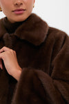 Person wearing the Dark Brown Faux Fur Brooke Cardigan with a wide collar, showcasing its classic, high-end design. An effortless touch on the lapel hints at fun sophistication.