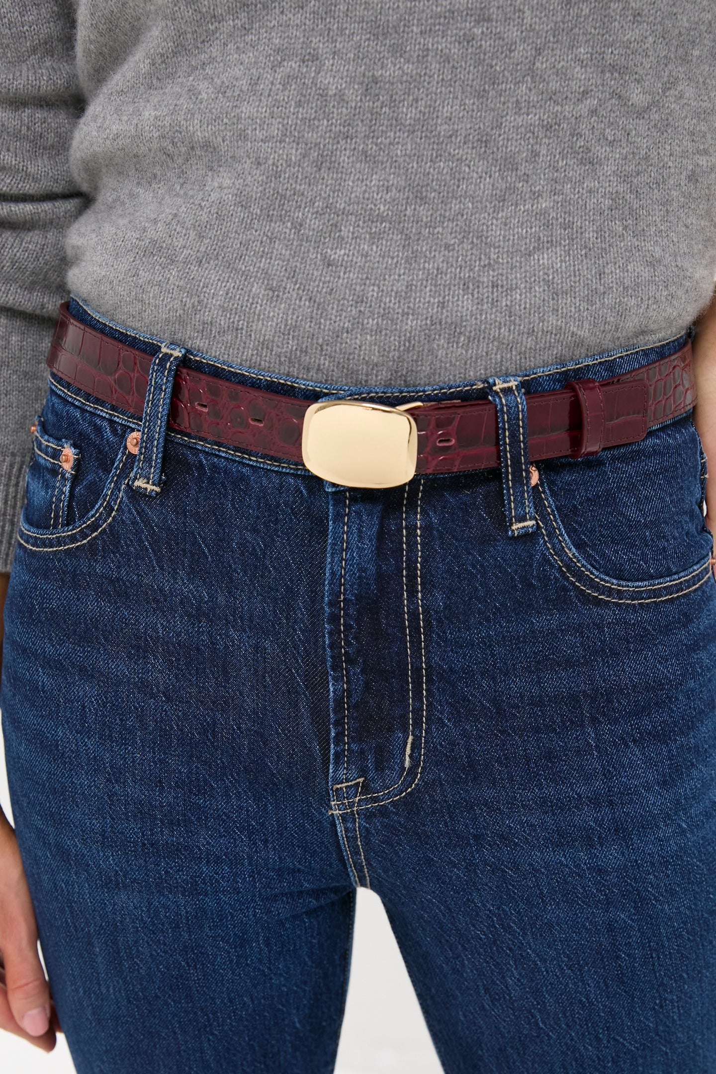 Merlot Jacob Croco Belt showcased with a classic light gray sweater and dark jeans, highlighting its high-end burgundy croc-embossed leather and effortless gold buckle for a fun, sophisticated touch.