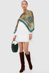 Woman in a white dress wearing classic, effortless Espresso Suede Goldy Boots; knee-high, chunky-heeled, paired with a chic botanical shawl and dark green handbag.