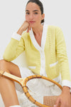 Young woman in Lemongrass Cable Charley Cardigan, styled with a tennis skirt and wooden racket, embodies classic, effortless, high-end fashion with fun, sporty details.