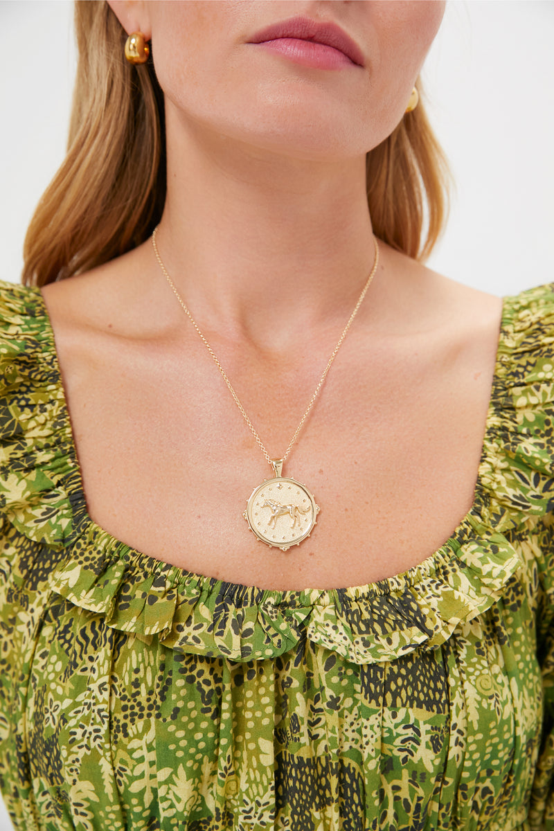 Classic Gold Courage Horse JW Original Pendant Coin on green ruffled blouse, showcasing an effortless and fun high-end style with a textured horse design and star details.