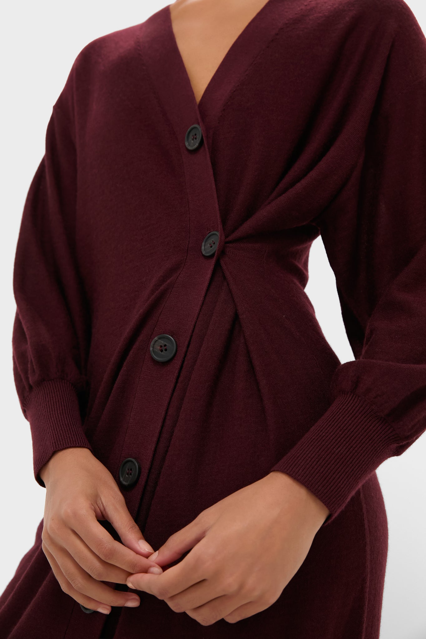 Person wearing the Mulberry Drippy Cardi Dress, a classic, effortless burgundy knit with twist detail, V-neck, and black buttons, embodying Tuckernuck's fun, high-end style.