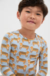 Child wearing Tigers Kids Bamboo Pj Set, featuring a fun cartoon-tiger motif on a classic light-blue top. The effortlessly cool set is soft, breathable, and high-end.