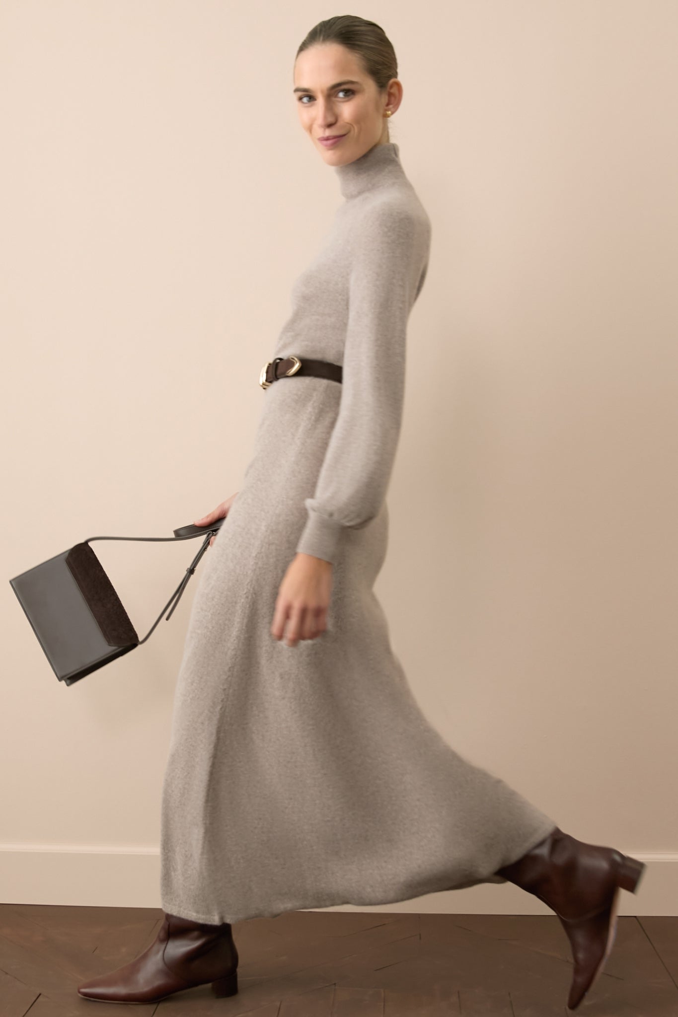 Woman wearing a long sleeved cashmere maxi dress with a belt around her waist. 