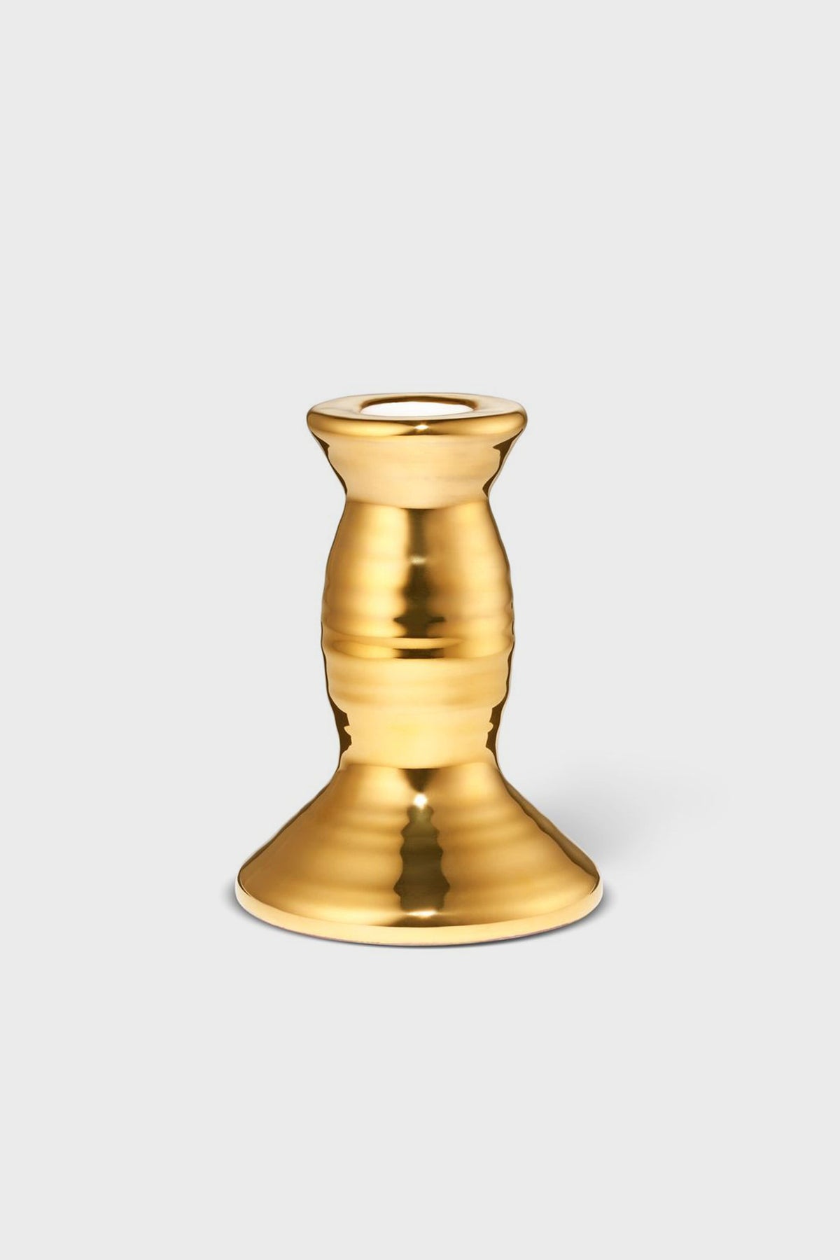 The AERIN gold-colored metallic candlestick holder features a wide base and rounded, tapered middle, adding artisanal elegance and craftsmanship to your home decor.