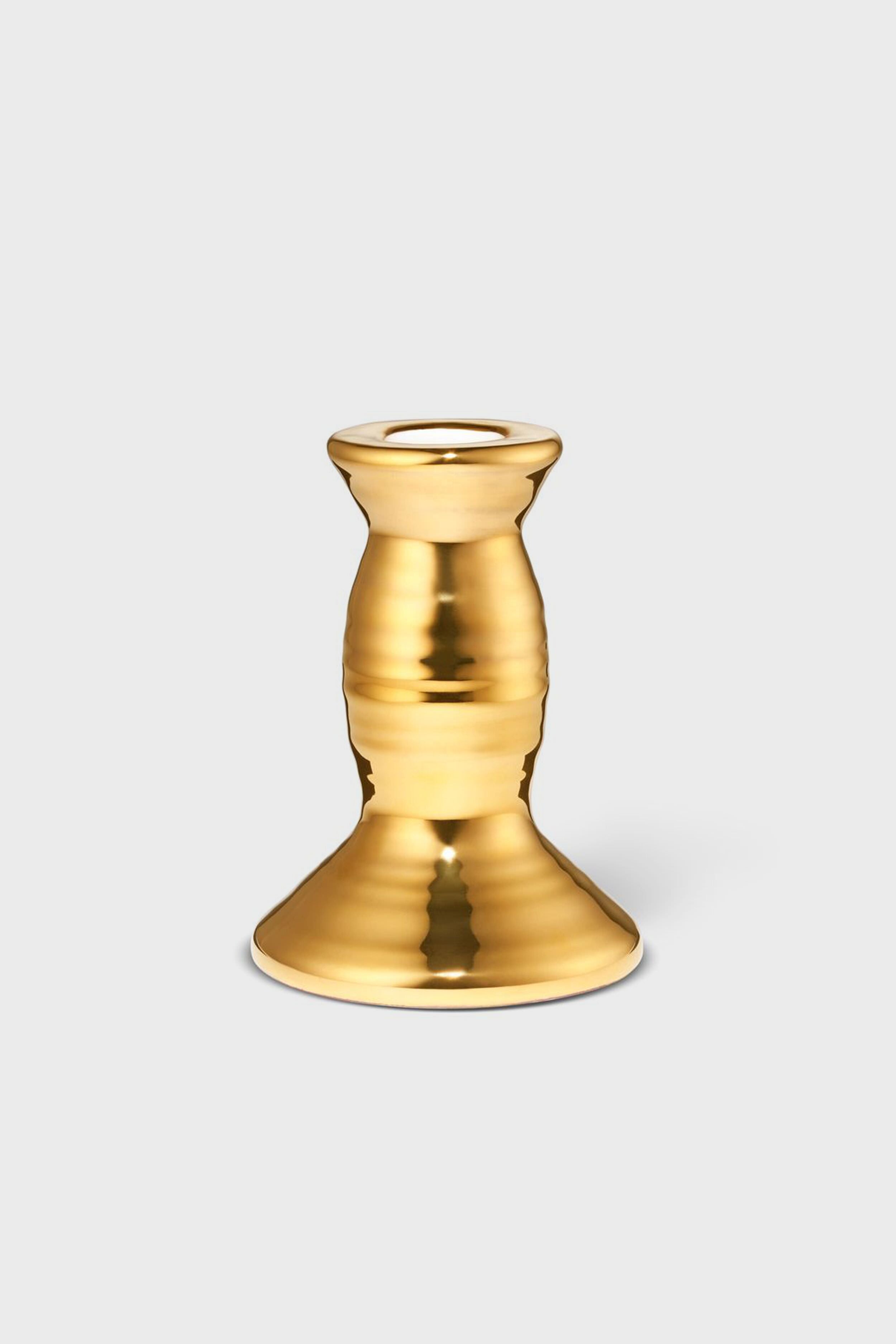 The AERIN gold-colored metallic candlestick holder features a wide base and rounded, tapered middle, adding artisanal elegance and craftsmanship to your home decor.
