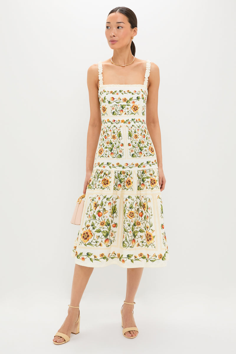 Model wears the classic Uchuva Nispero Midi Dress, featuring an effortless square neckline and ruffled straps, paired with a fun blush-pink handbag and high-end beige sandals.