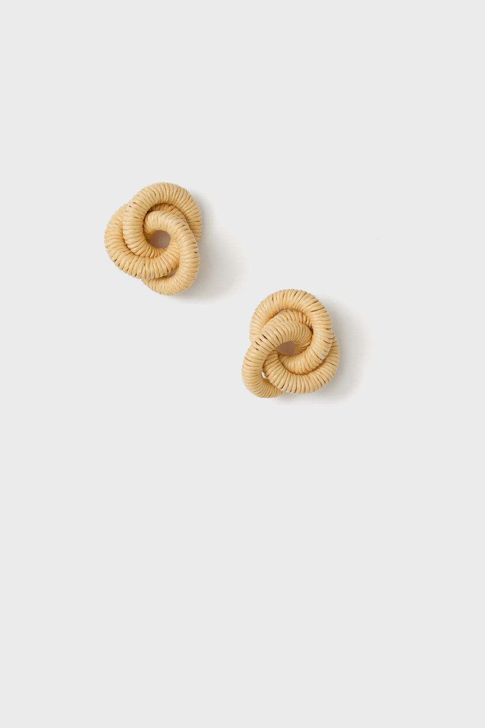 A pair of round, trinity knot earrings crafted from light tan woven raffia.