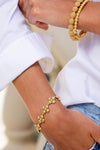 Close-up of a wrist wearing the Berry Clover Linear Bracelet, 7+2 - Gold, showcasing classic, effortless elegance with its fun, flower-like motifs, perfect for high-end layering.