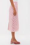 Soft Pink Shimmer Stripes Milan Midi Skirt features classic metallic diagonal stripes, paired effortlessly with pink velvet mules, embodying a fun and high-end, confident style.