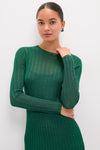 Young woman in a classic, high-end Green Shimmer Knit Cammie Maxi Dress, effortlessly showcasing its form-fitting elegance and subtle sheen, paired with fun, colorful stud earrings.