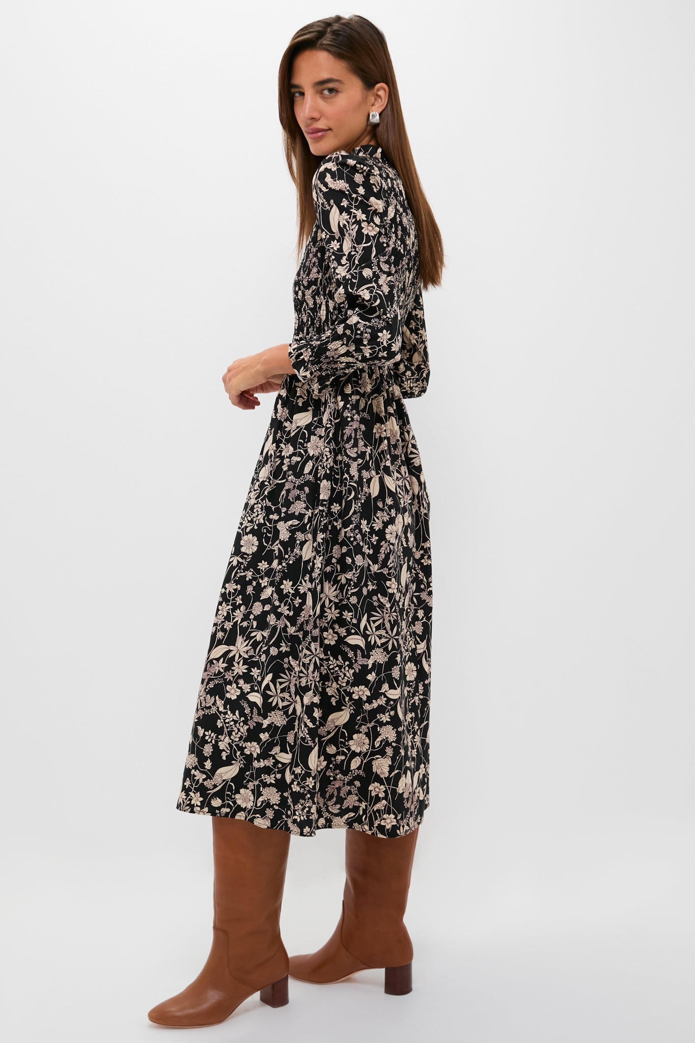 Woman in Black & Tan Floral Smocked Susanne Midi Dress, showcasing classic elegance with a smocked bodice and ruffle collar, paired effortlessly with warm brown leather boots.