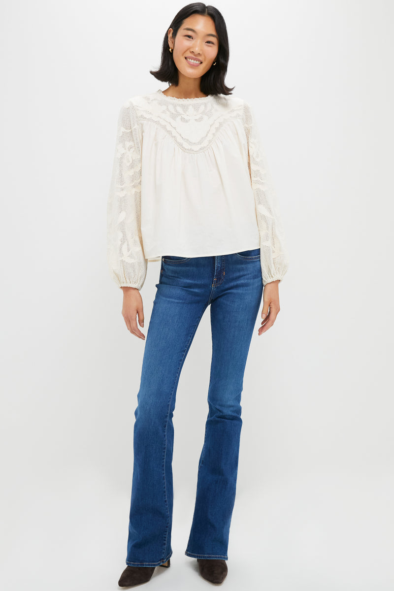 Woman models Ivory Patchwork Embroidered Cressida Blouse with intricate lace yoke and sleeves, paired with flared jeans and dark-brown ankle boots for a classic, effortless look.