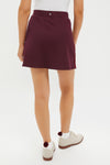 Model wearing the Winetasting 16 Inch Performance Stretch Woven Karrie Golf Skirt, showcasing a classic and effortless look with its high-rise design and fun, high-end details.