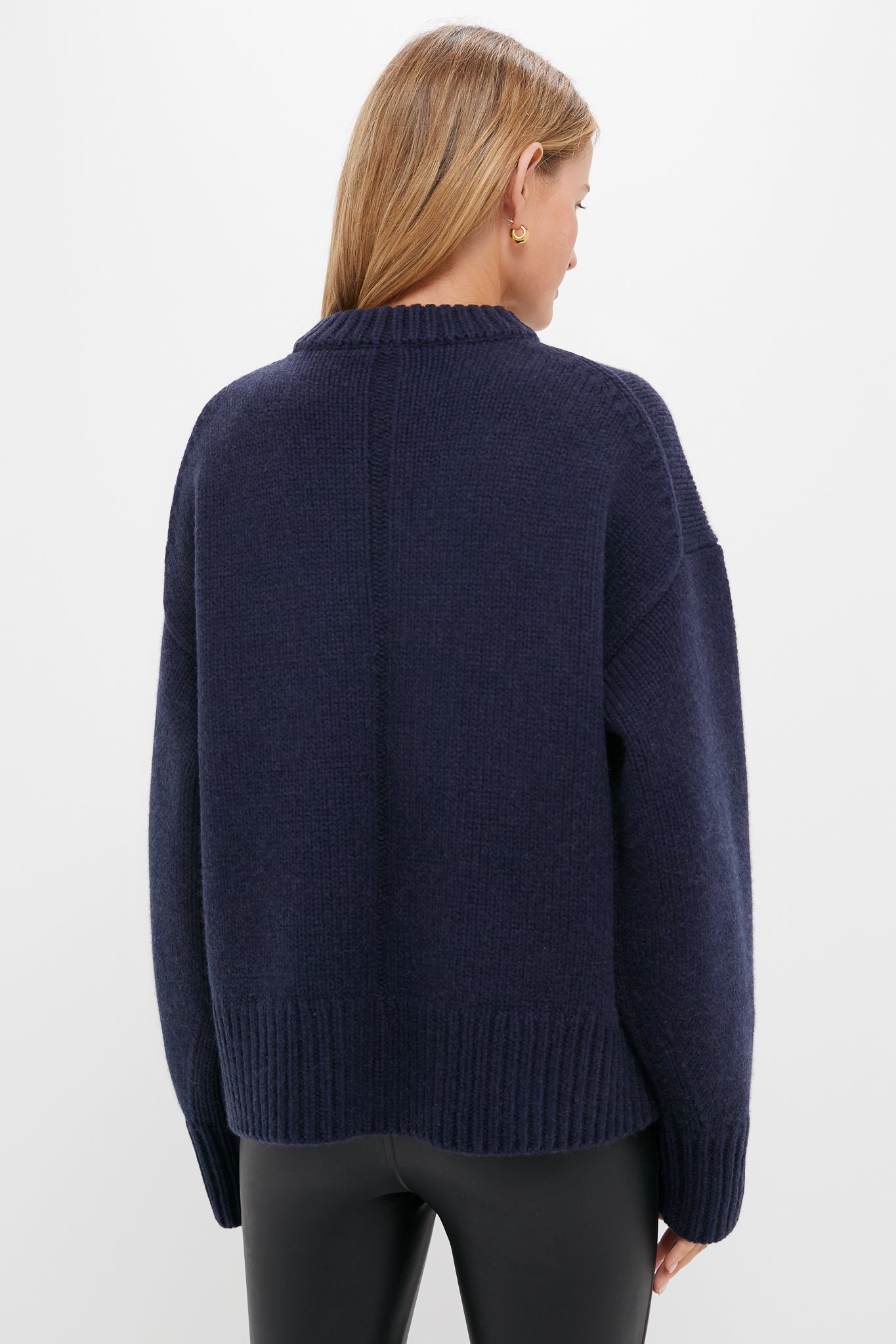 Back view of the Navy Genevieve Cashmere Wool Blend Crewneck Sweater, showcasing its classic, chunky knit and boxy fit, paired with black leather-look pants.