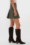 Olive Faux Leather Phillips Skirt with pleated A-line silhouette exudes classic, effortlessly cool style, paired perfectly with dark brown suede boots for a fun, high-end look.