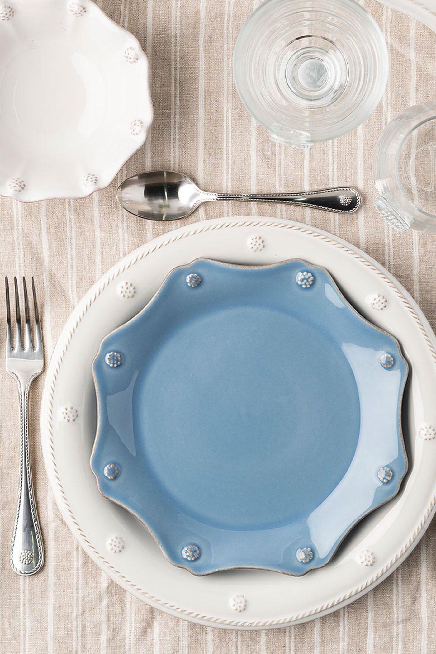 Chambray Berry & Thread Scalloped Dessert/Salad Plate in powder-blue, elegantly layered on an off-white charger, embodies classic, high-end style with effortless charm.