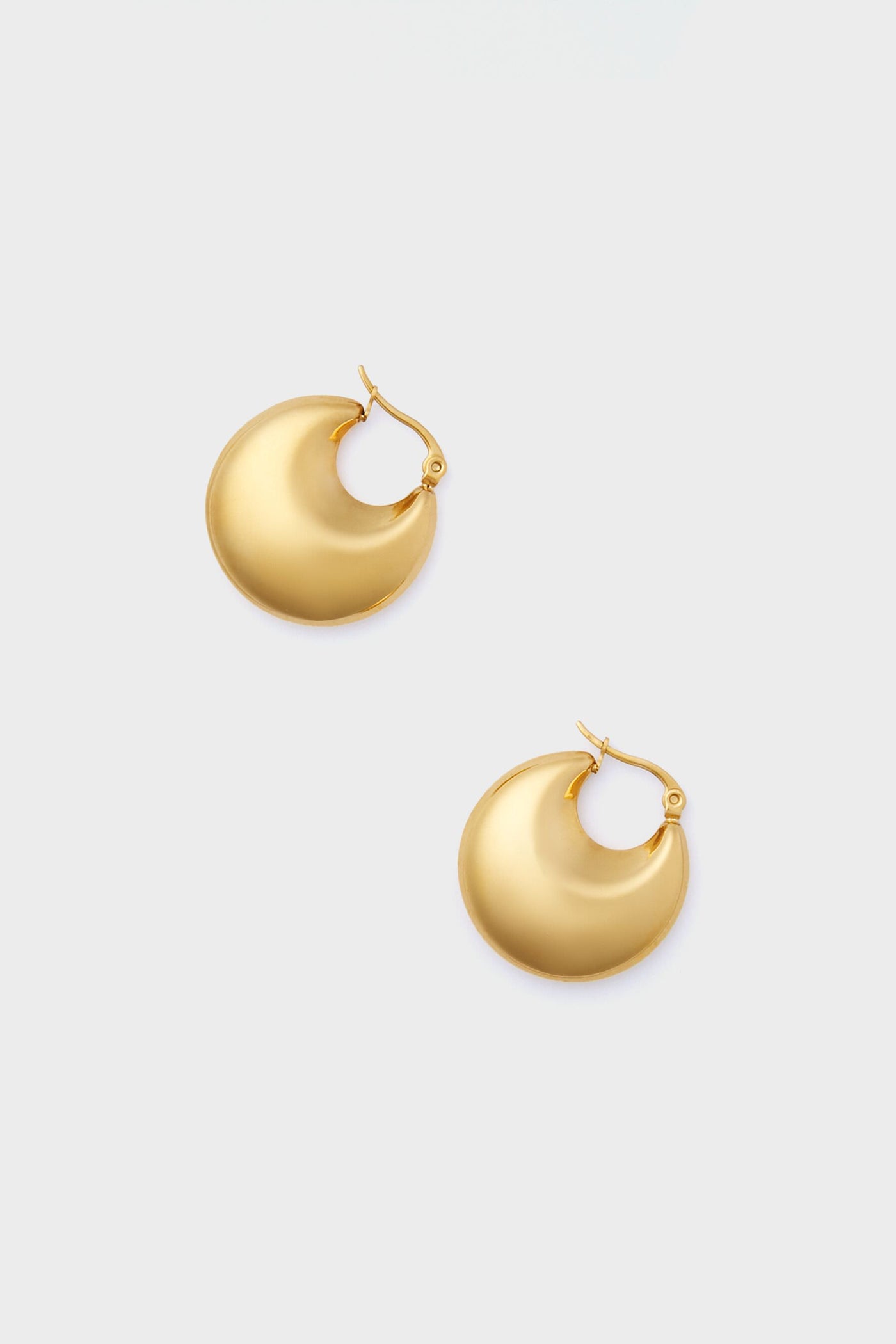 The Gold Lara Earrings by Petit Moments are chunky, round gold hoops with a latch back closure, crafted by a female-owned brand to add effortless elegance to any look.