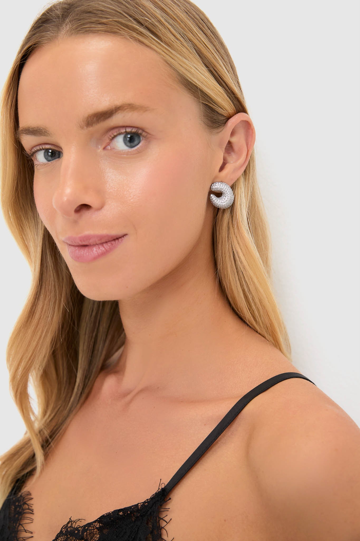 Young woman wearing Silver Crystal Vera Earrings, featuring chunky, pavé-style hoops, exuding classic, effortless glamour. Ideal for high-end events, complementing a modern, fun style.