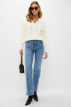Model in an Ivory Cable Knit Cropped Contessa V-Neck Sweater, classic and effortless, styled with jeans and brown accessories for a fun, high-end look.
