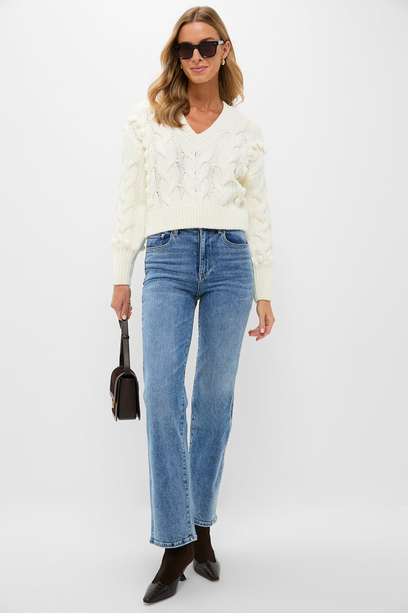 Model in an Ivory Cable Knit Cropped Contessa V-Neck Sweater, classic and effortless, styled with jeans and brown accessories for a fun, high-end look.
