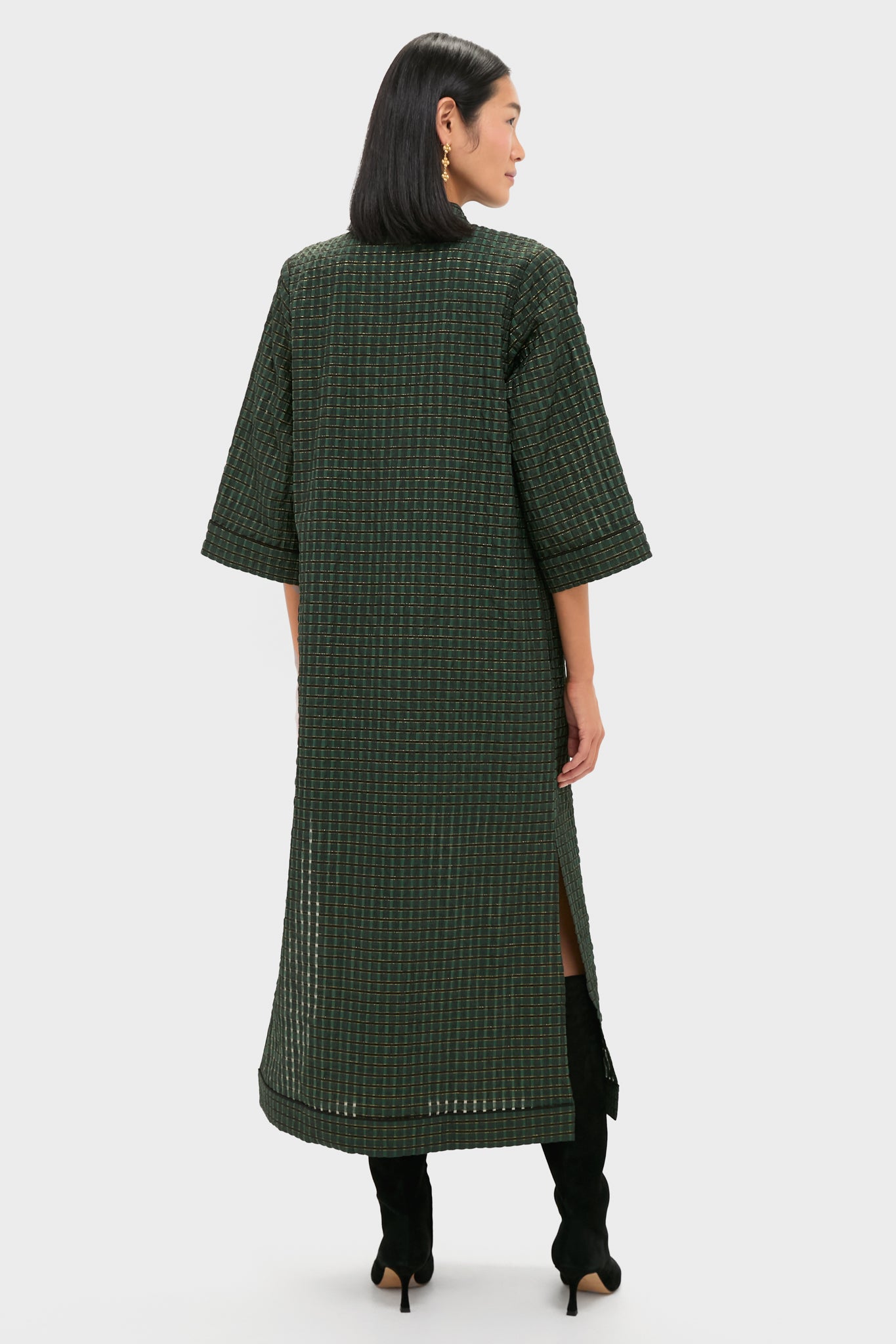 Woman wearing the classic Metallic Green Plaid Indy Maxi Dress with elbow-length sleeves and knee-high boots, exuding effortless style and high-end sophistication.